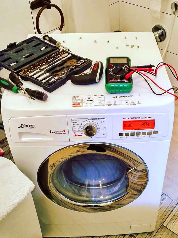 Стиральная машина со снятой верхней крышкой и инструмент мастера рядом